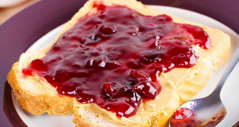 Eine Scheibe Toast mit roter Marmelade. | © Adobe Stock / Martin Rettenberger