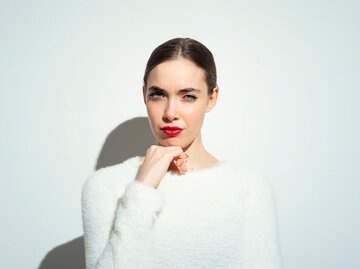 weiß gekleidete Frau auf weißem Hintergrund mit rotem Lippenstift schaut selbstbewusst in die Kamera | © Getty Images/Francesco Carta fotografo