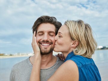 Frau küsst Mann auf die Wange und er ist glücklich | © Getty Images/Westend61