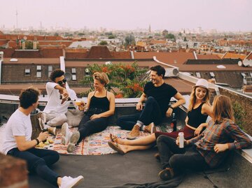Gruppe Menschen sitzen auf Dachterrasse | © Getty Images/Maskot