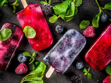 Einfaches und gesundes Sommerdessert. Hausgemachtes Beereneis am Stiel mit Minze. Mojito Lollypops, Frosen Diät mit Brombeere, Blaubeere und Himbeere infundiert. Dunkler Betonhintergrund Kopierraum Draufsich | © Getty Images/Rimma_Bondarenko