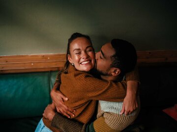 Paar sitzt im Cafe und umarmt sich glücklich. | © Getty Images / Alina Rudya/Bell Collective