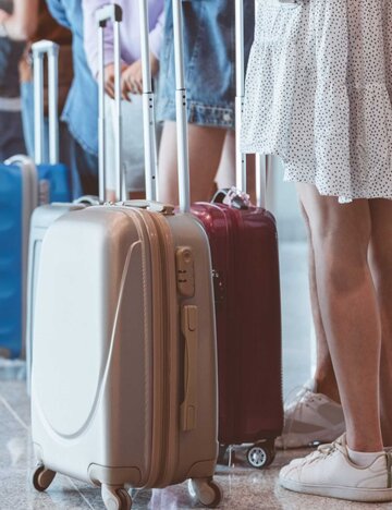 Passagiere mit Gepäck warten am Flughafen in der Schlange | © Getty Images/izusek