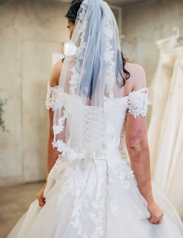 Frau trägt Brautkleid im Brautmodengeschäft | © Getty Images/South_agency