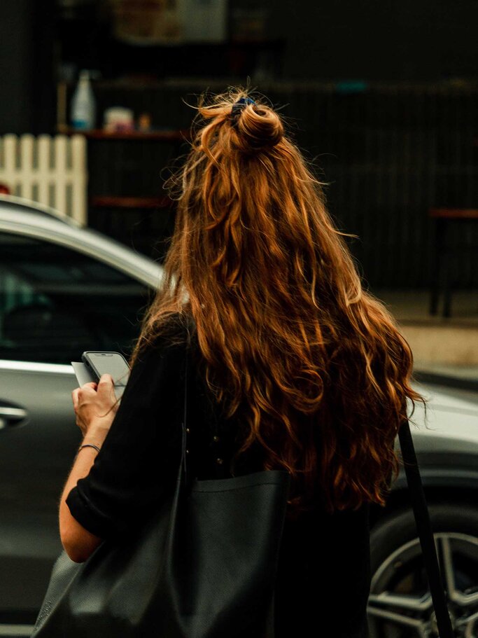 Frau mit rot-braunen Haaren von hinten aufgenommen, trägt einen Half-up-Bun. | © Adobe Stock/Pirate Samuel/Wirestock
