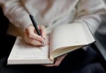 Hände einer Frau, die ihre Gedanken in ein Buch schreibt. | © GettyImages/Oksana Nazarchuk M