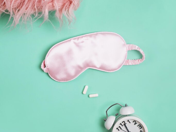 Rosa Schlafmaske, Wecker und zwei Pillen Top-Ansicht. | © gettyimages.de | Chiociolla