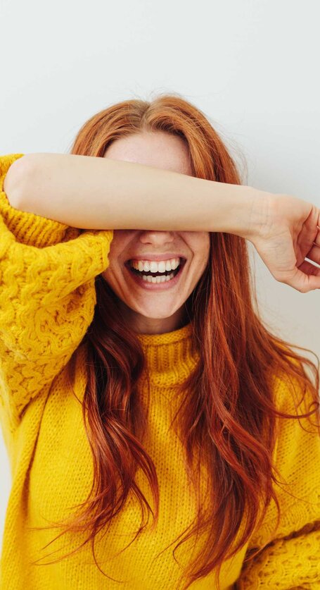 Frau hält sich vor Lachen den Arm vor das Gesicht | © Getty Images/stockfour