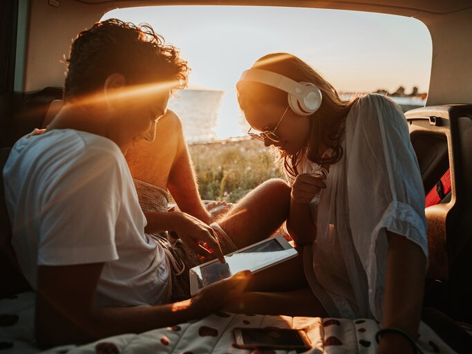 Junges Paar in einem Camper mit einem Tablet. | © gettyimages.de | Constantinis