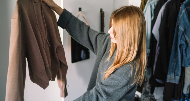 Frau hält Kleiderbügel mit Pulli nach oben | © Getty Images/All Nea / 500px