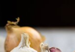 Knoblauch mit einer Zwiebel im Hintergrund | © iStock | Dash_med