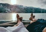 Frau und Mann liegen m Bademantel auf Liegestuhl am See mit Blick auf Bergpanorama | © iStock | Christopher Moswitzer