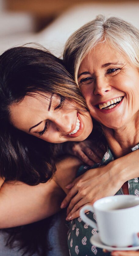 Liebevolle erwachsene Tochter umarmt fröhlich ihre Mutter | © iStock | wundervisuals