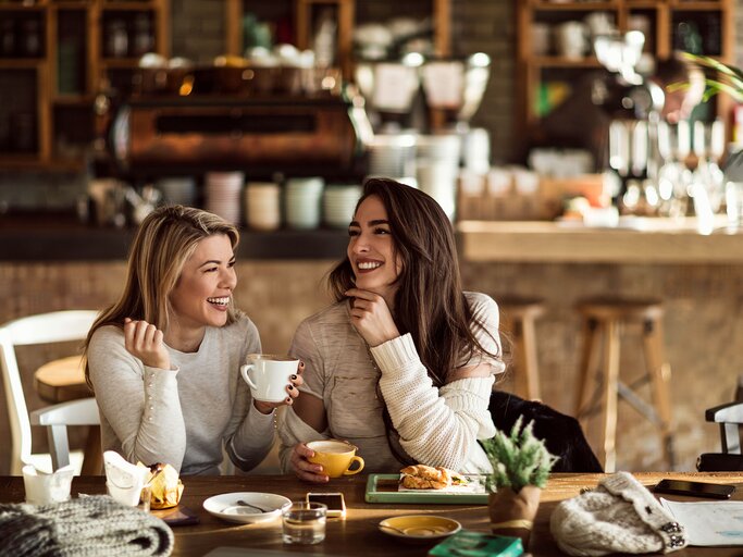 Junge Frauen unterhalten sich im Cafe | © iStock | Drazen Zigic