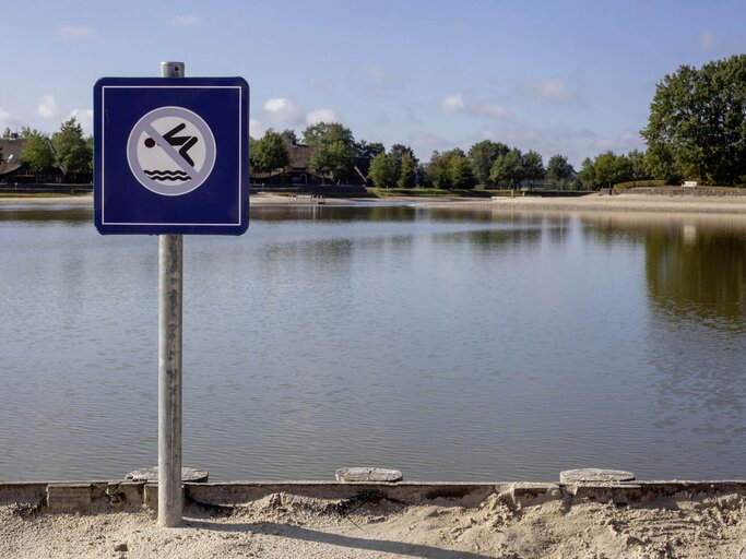 Ein "Nicht Schwimmen"-Gefahrenzeichen an einem See. | © iStock.com / janssenkruseproductions