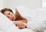 Frau liegt mit einer starken Grippe im Bett und hat Gliederschmerzen. | © gettyimages.de / Martin Barraud