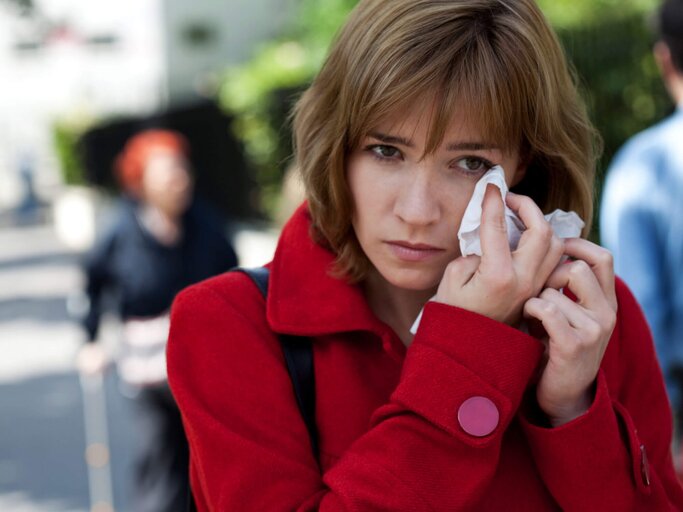 Frau hält sich ein Taschentuch an die Augen, da diese wegen eine Bindehautentzündung tränen. | © gettyimages.de / BSIP