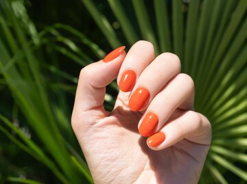 Fingernägel mit  Nagellack in der Farbe Orange | © GettyImages/DevMarya