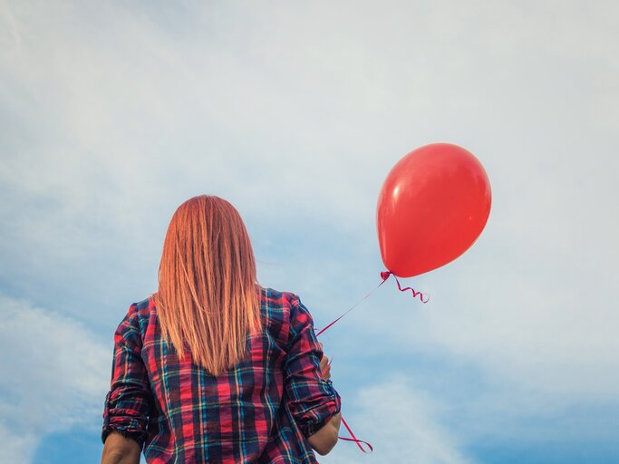 Junge Frau mit Luftballon in der Hand | © Getty Images/LumineImages